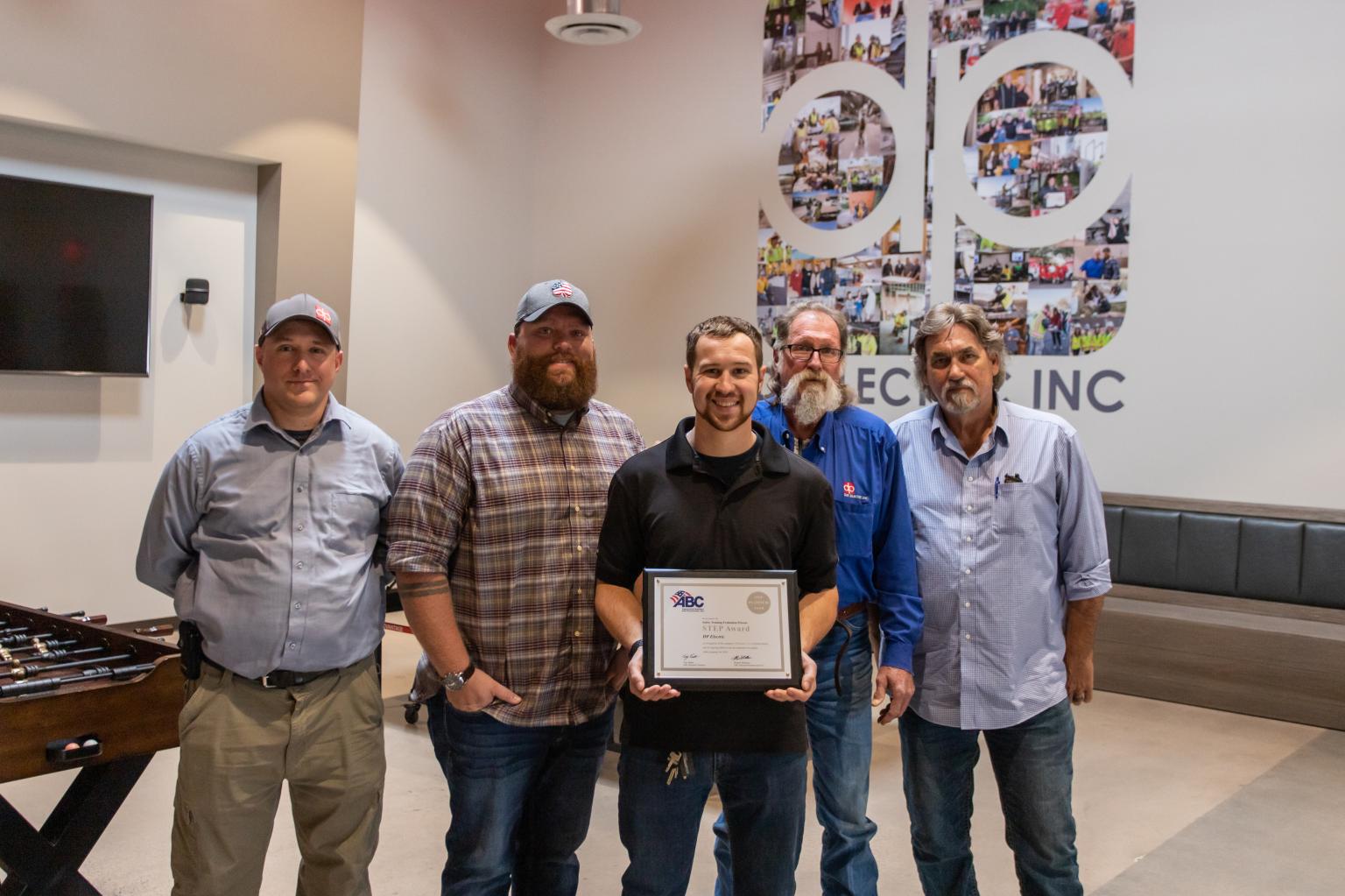 A group of men posing for a picture with an award at DP Electric.