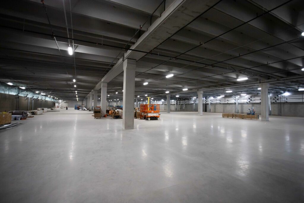 The inside of a large warehouse with concrete floors and a forklift, showcasing Edgecore technology.