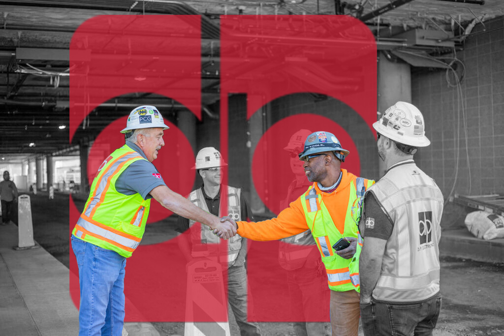 A group of construction workers shaking hands in front of a red sign symbolizing home.