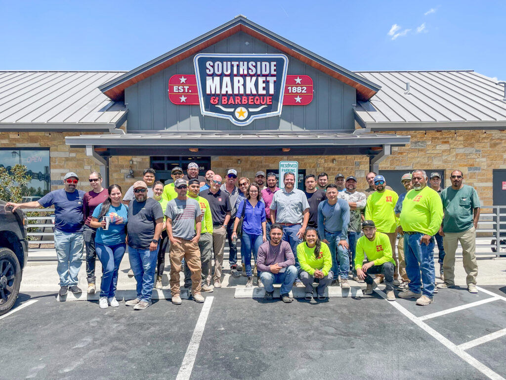 A group of people posing in front of a market while DP Electric announces their exciting new venture into Austin, Texas.