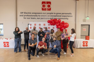 A group of people from DPE Electric posing for a picture in front of balloons.